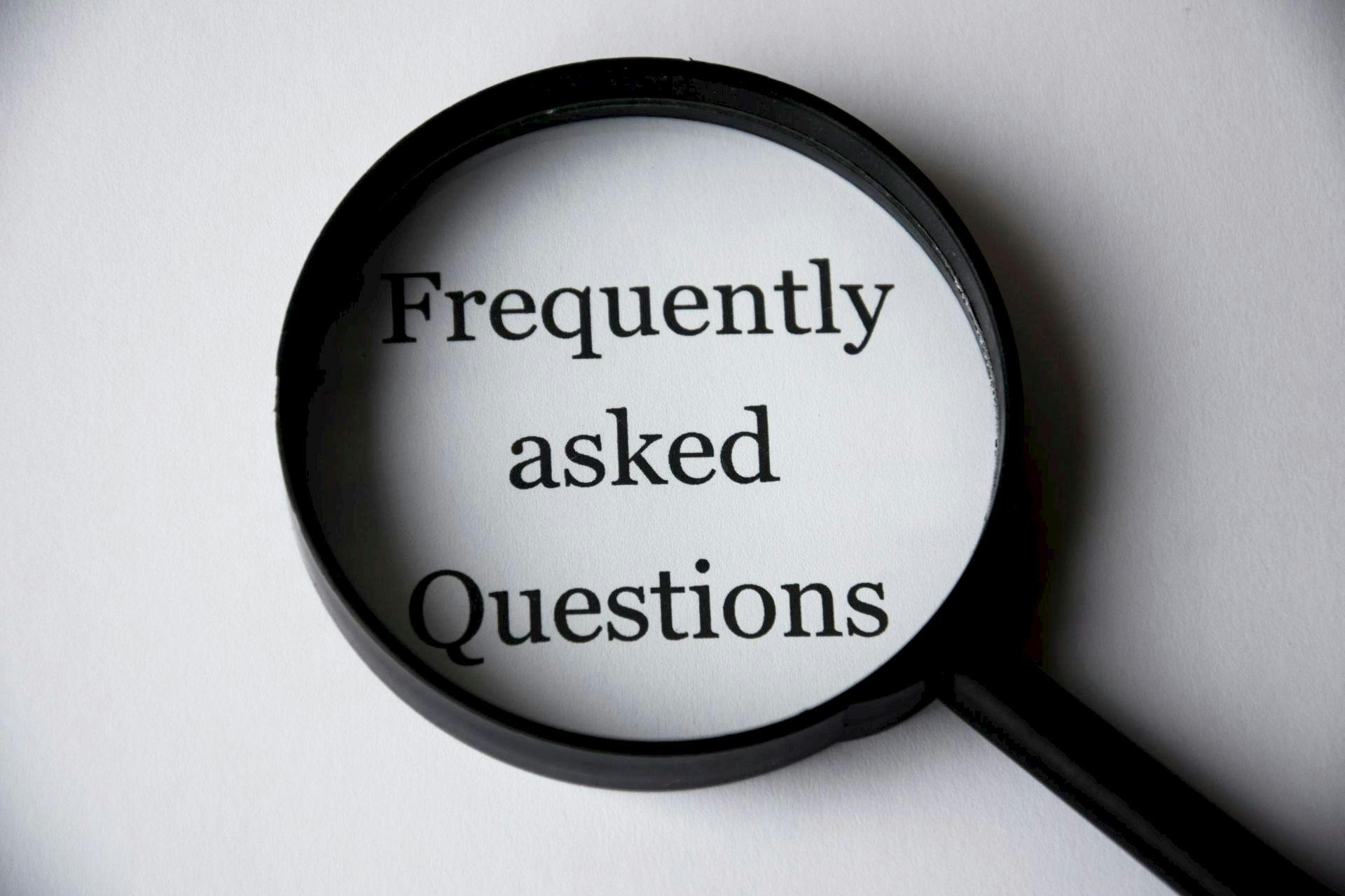 FAQ image with magnifying glass highlighting frequently asked questions about Business Startup Loan, Merchant Loan, Working Capital, and Business Purchase Loan financing options for business owners.
